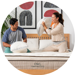 Man and woman playing with pillows on a mattress